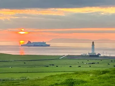 a cruise ship in the ocean with a lighthouse and a light house at Seascape Barn in Kirkcolm