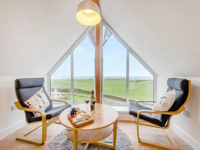 a living room with two chairs and a table and a window at Seascape Barn in Kirkcolm