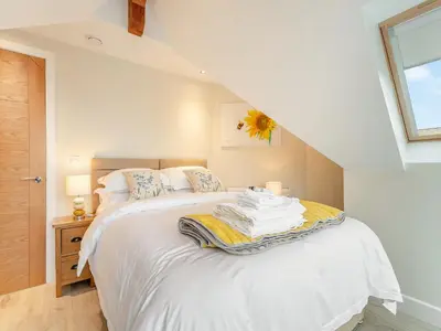 a bedroom with a bed with white sheets and a window at Seascape Barn in Kirkcolm