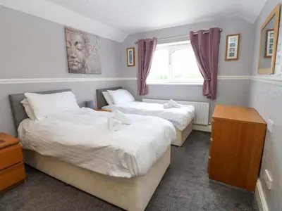 two beds in a small room with a window at Fern Lee in Carlisle