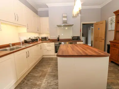 a kitchen with white cabinets and a wooden counter top at Fern Lee in Carlisle