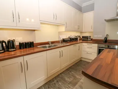 a kitchen with white cabinets and a wooden counter top at Fern Lee in Carlisle