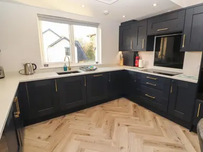 a kitchen with black cabinets and a wooden floor at Mallard Cottage in Penrith