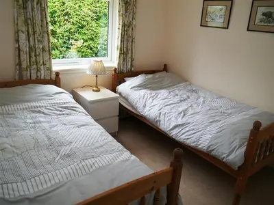 two twin beds in a room with a window at Seabank Cottage in Rockcliffe