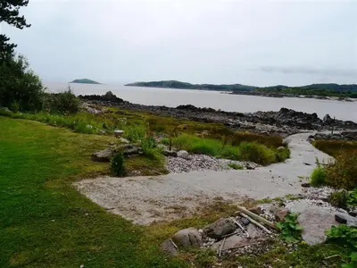 a path through a field with a body of water at Seabank Cottage in Rockcliffe