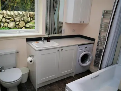 a bathroom with a toilet sink and a washing machine at Seabank Cottage in Rockcliffe