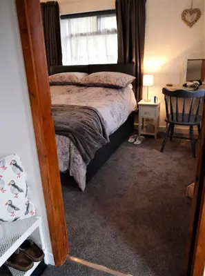 a bedroom with a bed and a window and a chair at Kippford Stables in Kippford