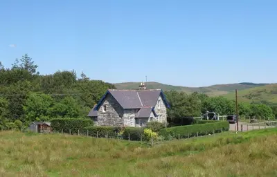 an old house on a hill in a field at Rowantree Cottage in Gatehouse of Fleet