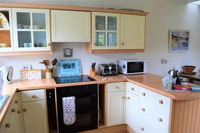 a kitchen with white cabinets and a black oven at Rowantree Cottage in Gatehouse of Fleet