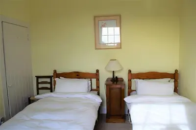 a bedroom with two beds and a picture on the wall at Rowantree Cottage in Gatehouse of Fleet