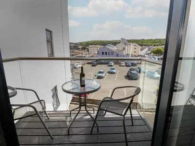a table and chairs on a balcony with a bottle of wine at Harbourside Apartment - 1 Bedroom - Sleeps 2 in Whitehaven