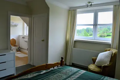 a bedroom with a bed and a window and a chair at Portling View in Dalbeattie
