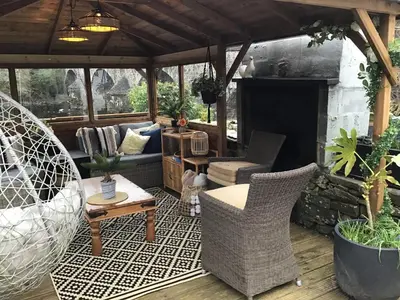 a patio with wicker chairs and a fireplace at The Haven B&B in Castle Douglas