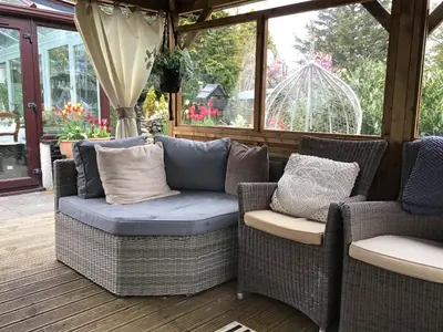 a porch with two wicker chairs and a couch at The Haven B&B in Castle Douglas