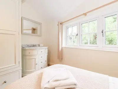 a bedroom with a bed and a sink and windows at Holly Cottage in Ambleside