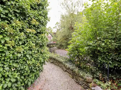 a hedge with a walkway through a garden at Holly Cottage in Ambleside