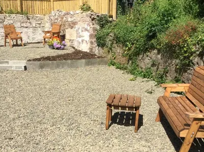 a patio with two wooden benches and a stool at Wee Dipper Cottage Maybole in Maybole