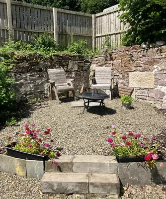 a garden with two chairs and a table and flowers at Wee Dipper Cottage Maybole in Maybole