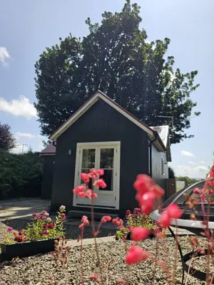 a small black shed with flowers in front of it at Wee Dipper Cottage Maybole in Maybole