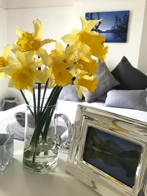 a vase of yellow flowers sitting next to a picture frame at Roses Cottage cosy countryside home with open fire and mountain views near Scafell in Santon Bridge
