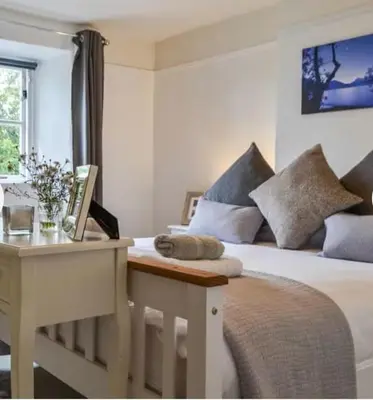 a bedroom with a bed with a desk and a bed sidx sidx sidx at Roses Cottage cosy countryside home with open fire and mountain views near Scafell in Santon Bridge