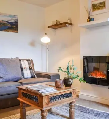 a living room with a couch and a fireplace at Roses Cottage cosy countryside home with open fire and mountain views near Scafell in Santon Bridge