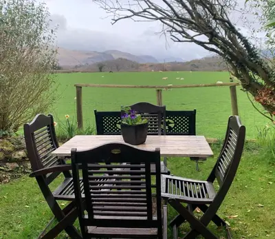a wooden table and chairs with a potted plant on it at Roses Cottage cosy countryside home with open fire and mountain views near Scafell in Santon Bridge