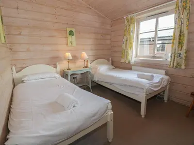 two beds in a wooden room with a window at Lapwing Lodge in Dumfries