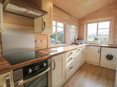 a kitchen with white cabinets and a stove at Lapwing Lodge in Dumfries