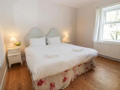 a bedroom with a large bed with white sheets and a window at West Lodge in Dumfries