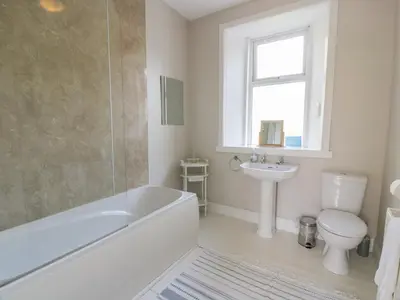 a bathroom with a tub and a toilet and a sink at West Lodge in Dumfries