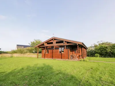a small wooden cabin in a field of grass at Curlew Lodge in Dumfries