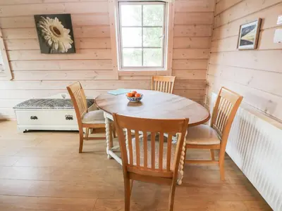 a dining room with a wooden table and chairs at Curlew Lodge in Dumfries