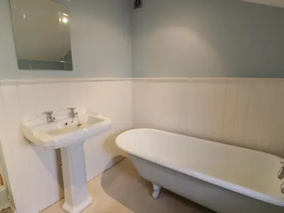 a white bathroom with a sink and a bath tub at Little Dunbar Cottage in Dumfries