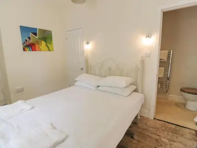 a white bedroom with a bed and a toilet at Little Dunbar Cottage in Dumfries