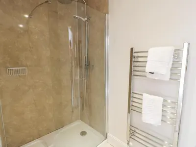 a bathroom with a shower with a glass door at Little Dunbar Cottage in Dumfries