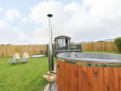 a hot tub in a yard with a fence at Greenacres Carriage in Maybole