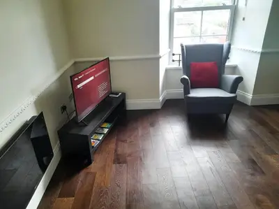 a living room with a tv and a chair at Kirkcudbright Holiday Apartments - Apartment F in Kirkcudbright