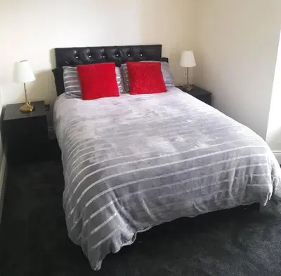 a bedroom with a large bed with two red pillows at Kirkcudbright Holiday Apartments - Apartment F in Kirkcudbright