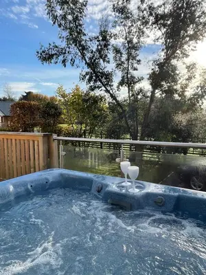 a jacuzzi tub with two glasses in it at Sparrowhawk Cottage with Hot Tub in Newton Stewart