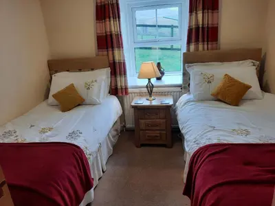 two twin beds in a room with a window at Laghead Steading Cottage in Gatehouse of Fleet