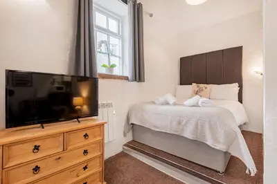a bedroom with a bed and a flat screen tv at cottage 7 old farmhouse mews in Keswick