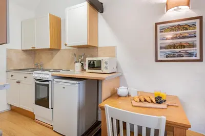 a small kitchen with a table and a microwave at cottage 7 old farmhouse mews in Keswick
