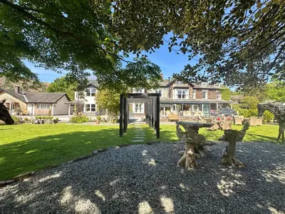 a park with a bench in front of a house at Bridge House Hotel & Silver Howe View Cottage in Grasmere