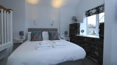 a bedroom with a large white bed with towels on it at Braithwaite House Rooms in Braithwaite