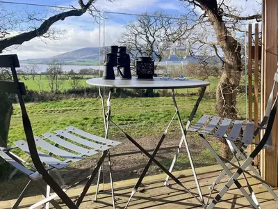 a table and two chairs on a porch at The Treehouse Caerlaverock - Uk45028 in Carsethorn