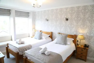 two beds in a room with two windows at Keswick Park Hotel in Keswick