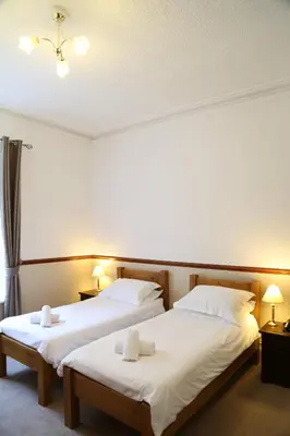 two beds in a hotel room with white sheets at Keswick Park Hotel in Keswick