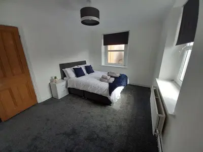 a bedroom with a bed with blue pillows and a window at Ennerdale Edge - 4 Bedrooms - Sleeps 8 in Cleator Moor