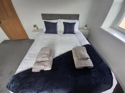 a bedroom with a large bed with blue pillows at Ennerdale Edge - 4 Bedrooms - Sleeps 8 in Cleator Moor